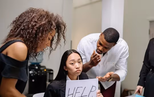Woman holding a sign that says help while people are standing around her and talking to her.