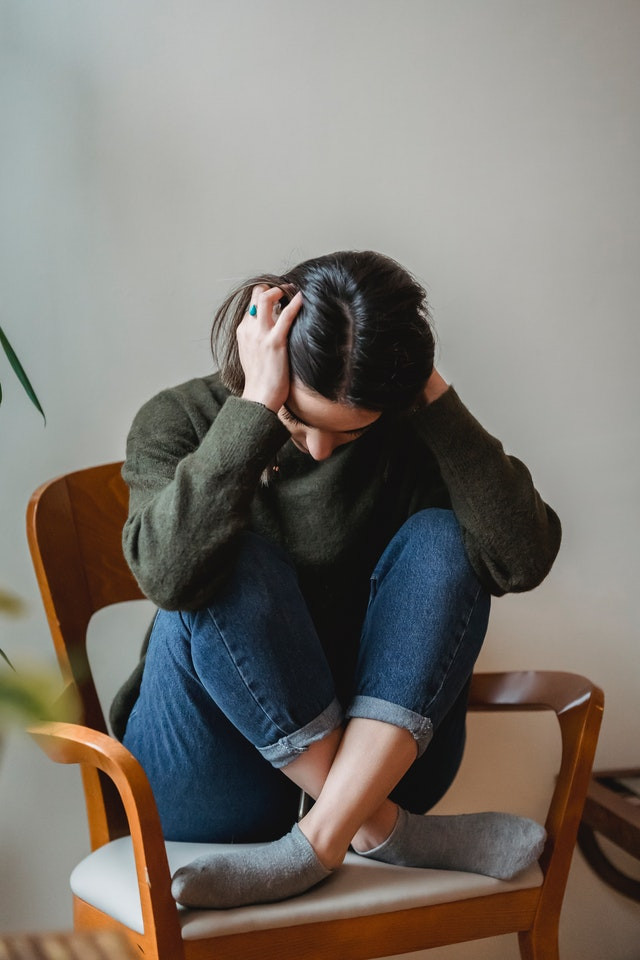 Woman sitting in a chair holding her head down
