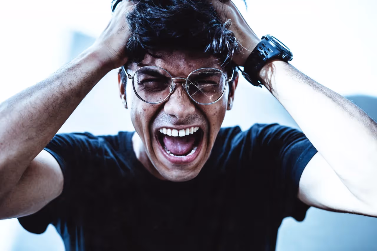 a man with glasses screaming while pulling his hair