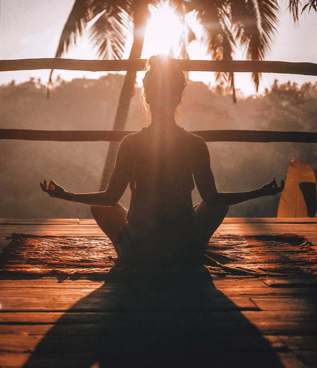a woman sitting outside on a wooden deck meditating