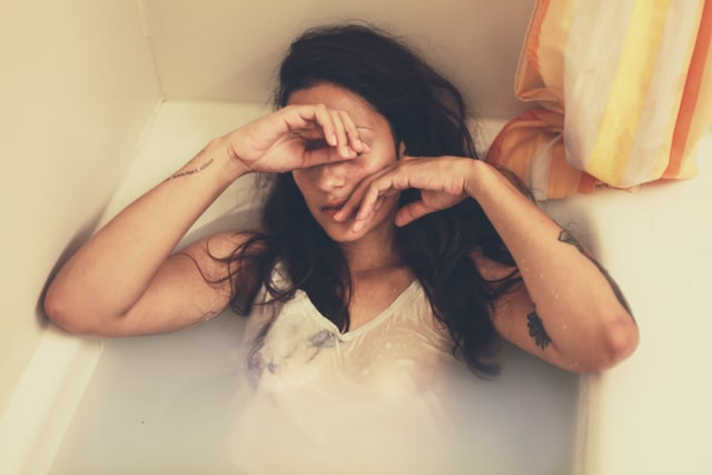 A woman sitting in a bath tub looking stressed