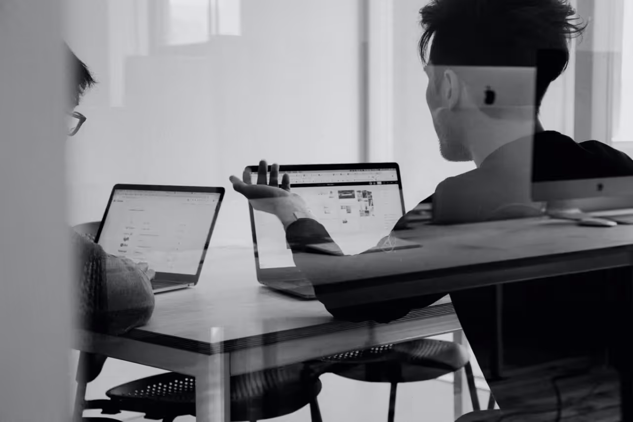 Two people sitting at a table working on laptop computers