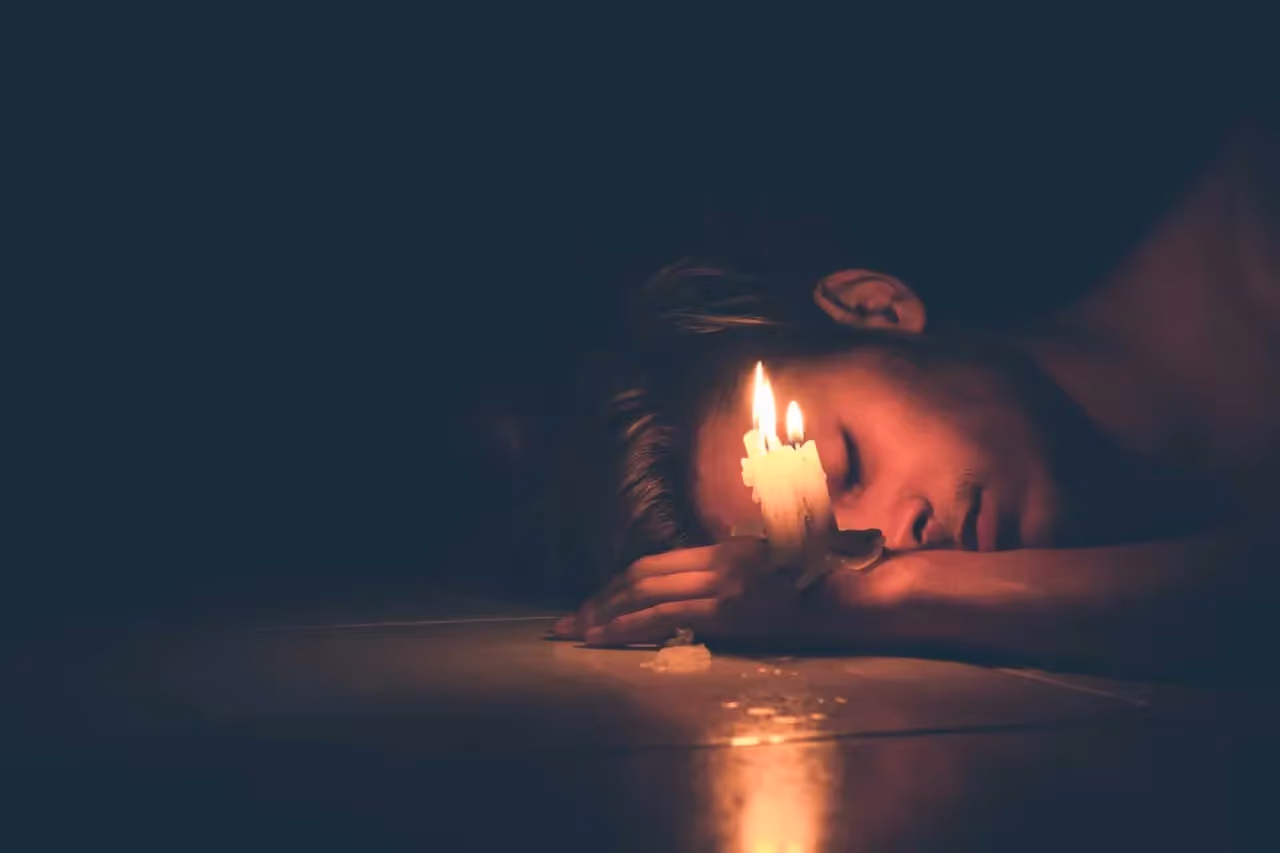 a person lying on the ground next to a candle