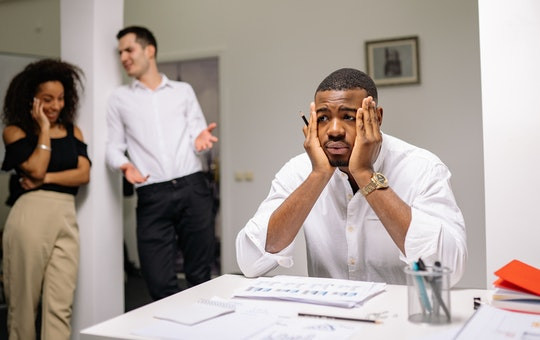 Man sitting at a table at work with his hands on his face looking sad
