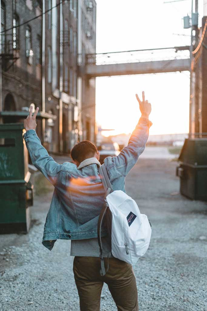 a person walking down an alley triumphantly raising their hands