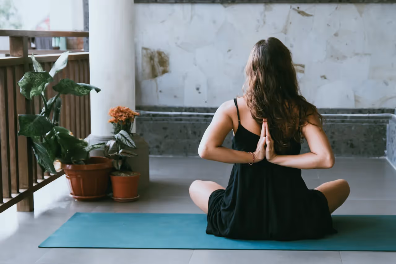 Woman sitting on a green mat meditating.