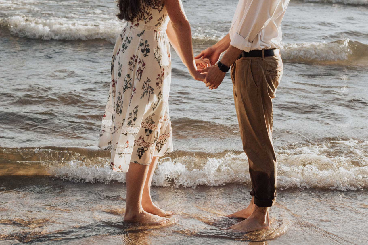couples looking at each other while standing on a beach