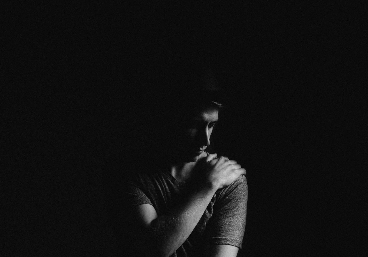 a lone man soothing with a self hug looking down