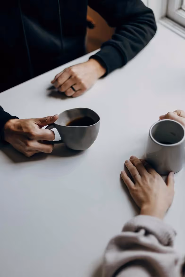 two people sitting across from eachother with coffee