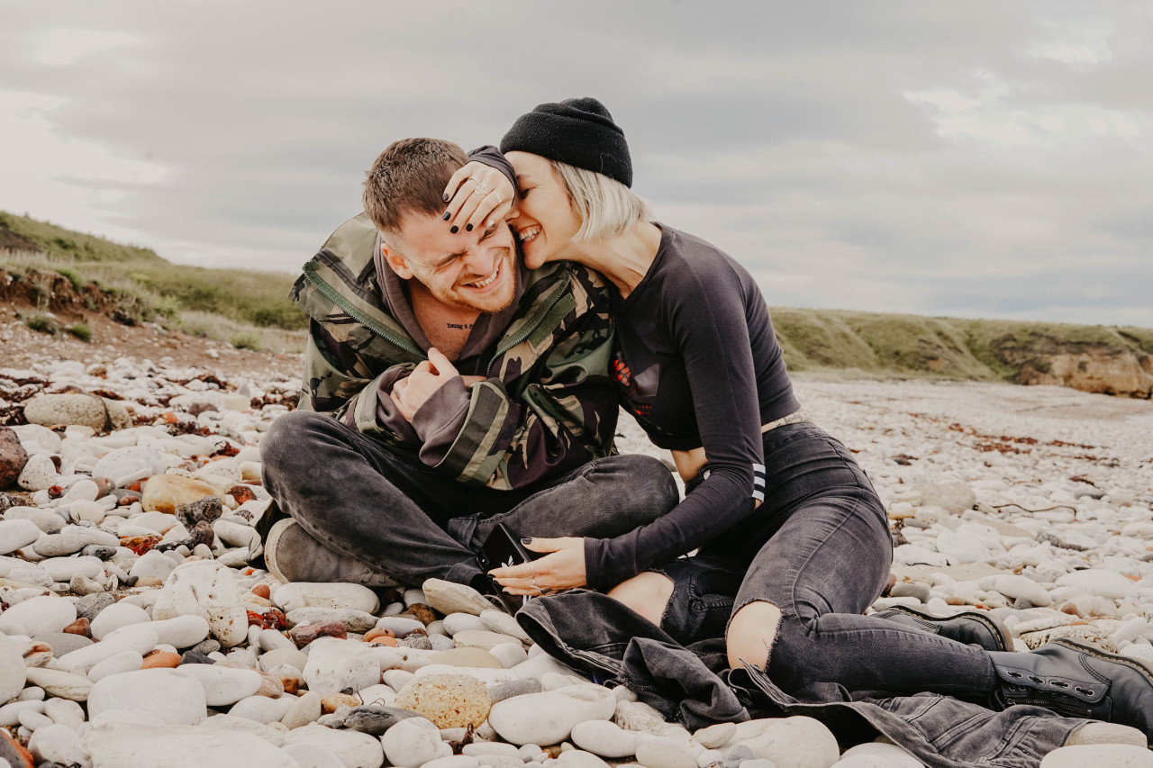 A couple sitting on rocks laughing with eachother
