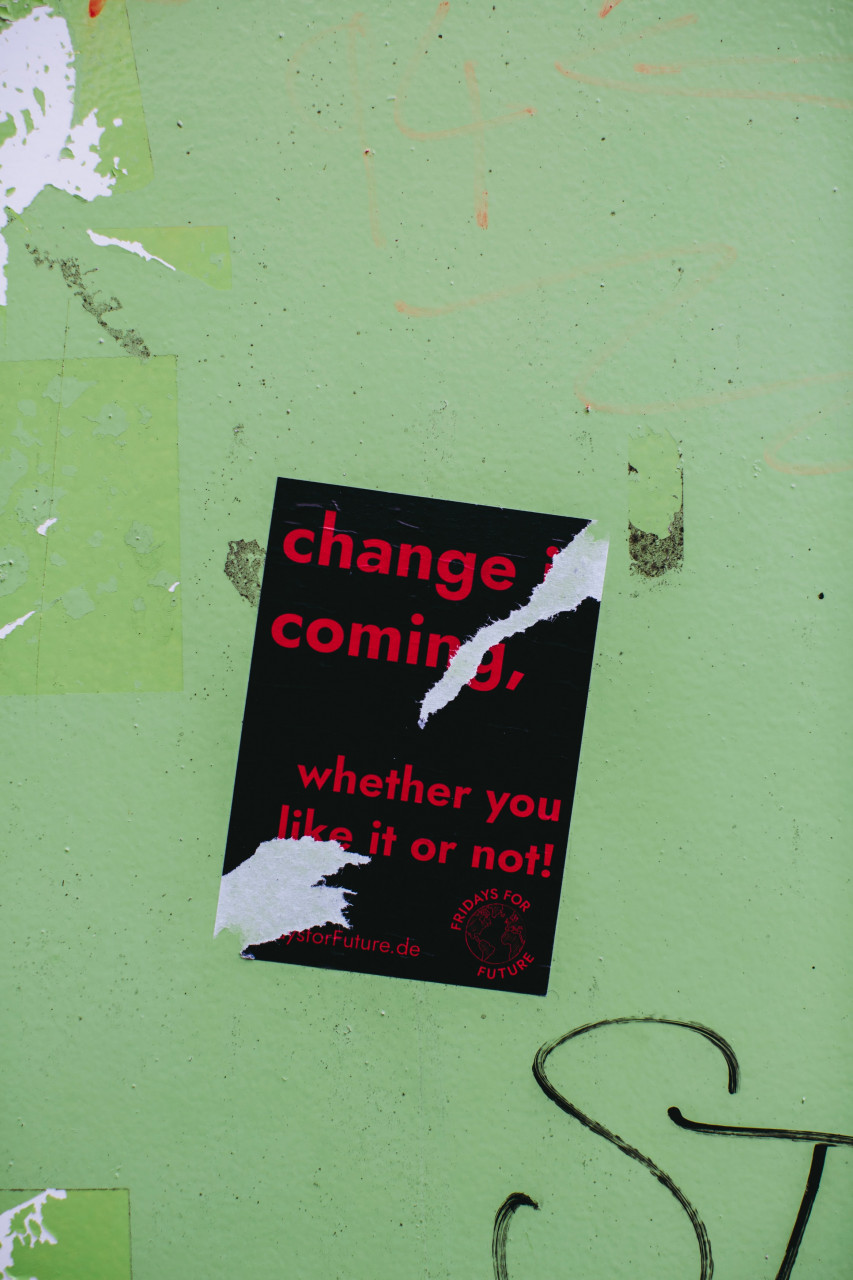 Poster on a green wall that says change is coming, whether you like or not