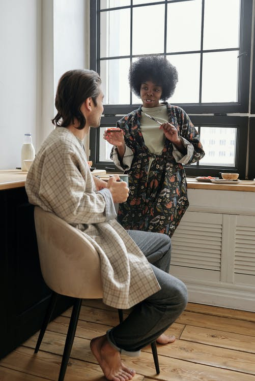 Woman speaks to man in chair.