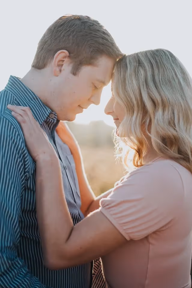 a man and woman standing outside leaning their foreheads against each other