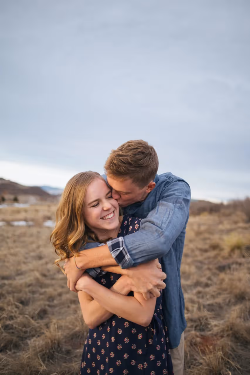 A man holding a woman and kissing her on the cheek