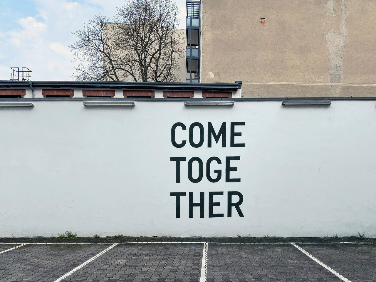 A white wall with the words come together in black