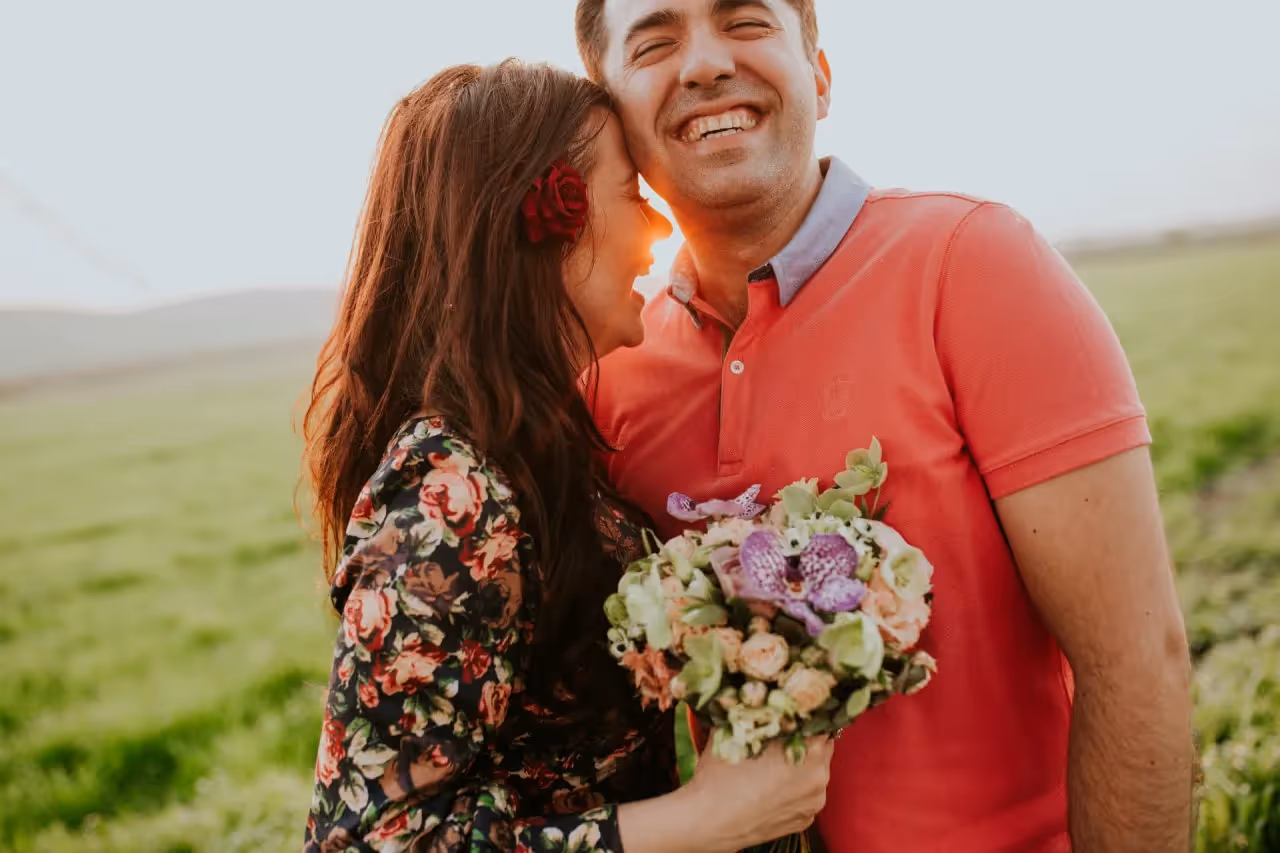 A woman holding a bouquet of flowers while laughing with her partner