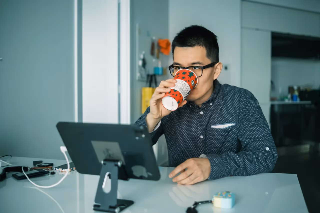 A man sitting at his desk drinking coffee