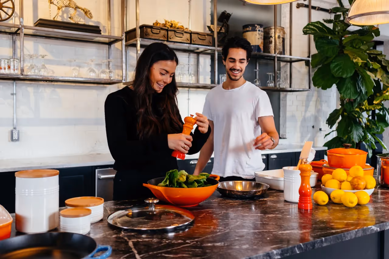 A couple in the kitchen making a meal together.