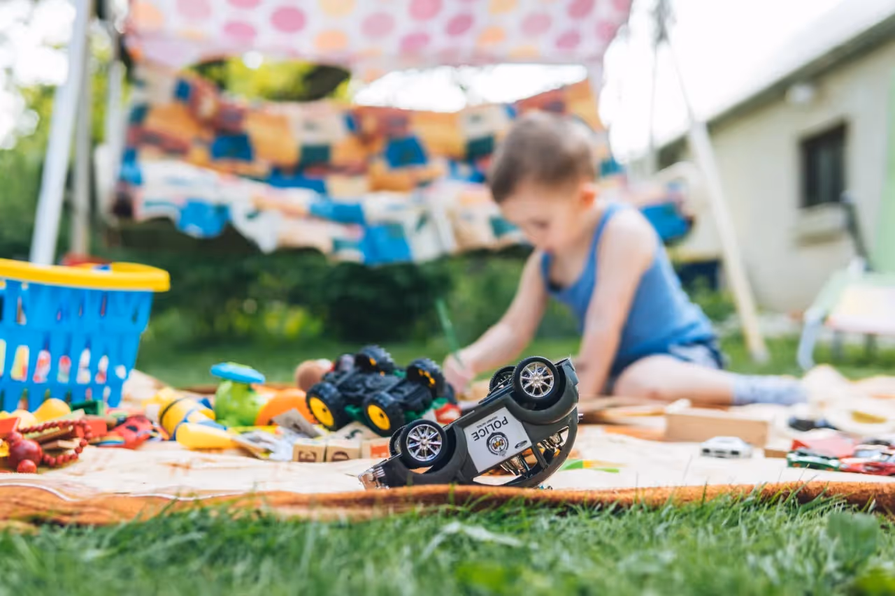 Boy playing with toys outside on a blanket