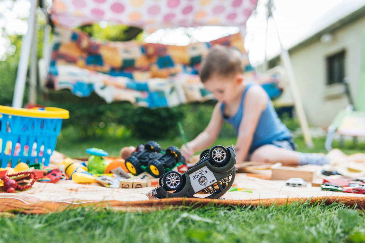 Boy playing with toys outside on a blanket