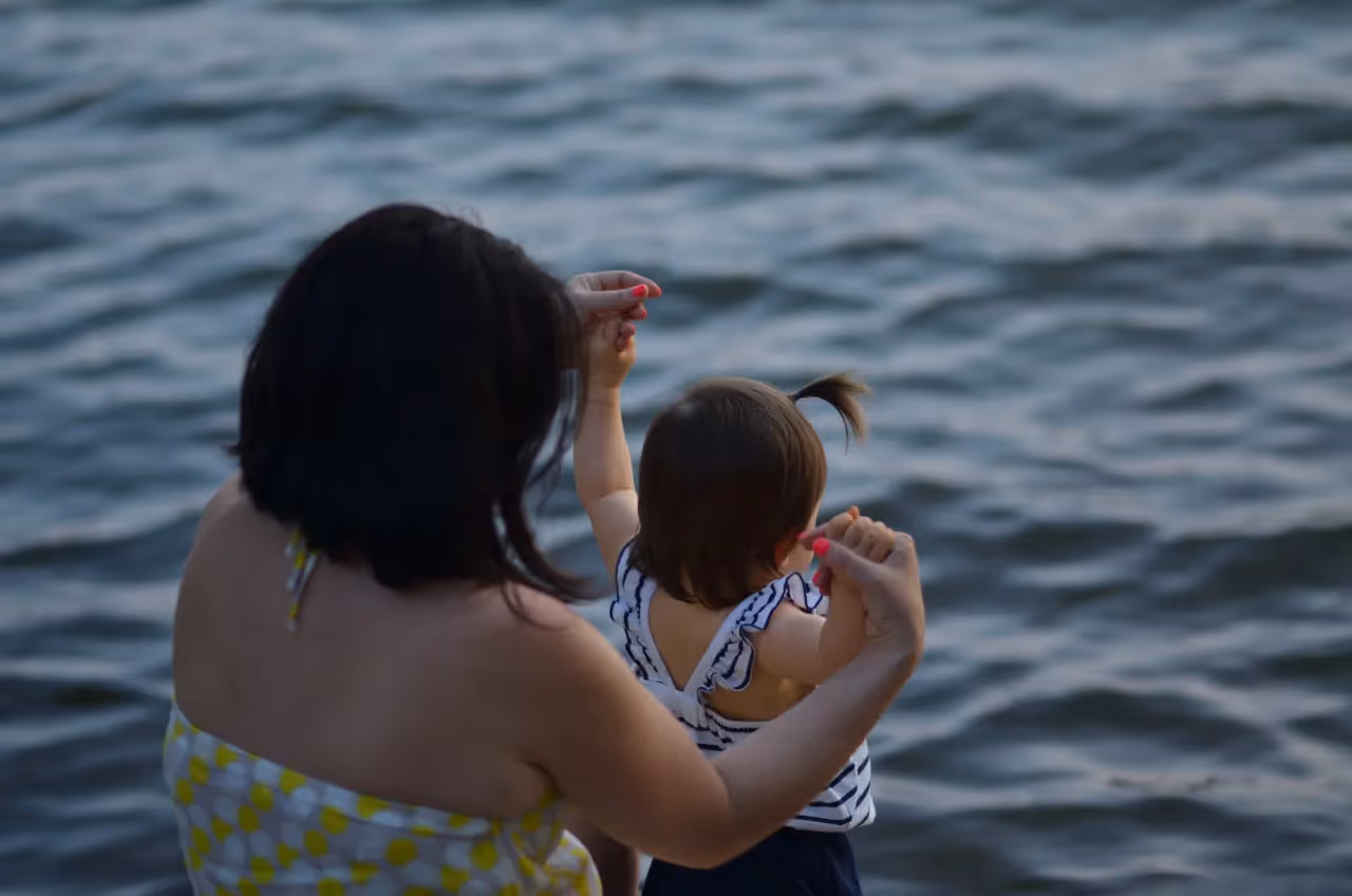 A mother with her daughter in water.