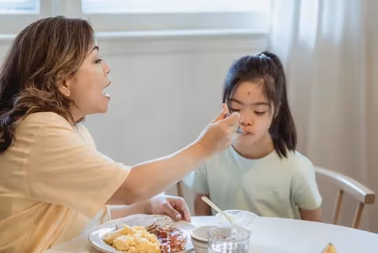 Mom feeding her daughter breakfast at the table