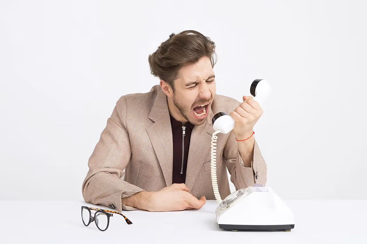 An angry man screaming at the phone.
