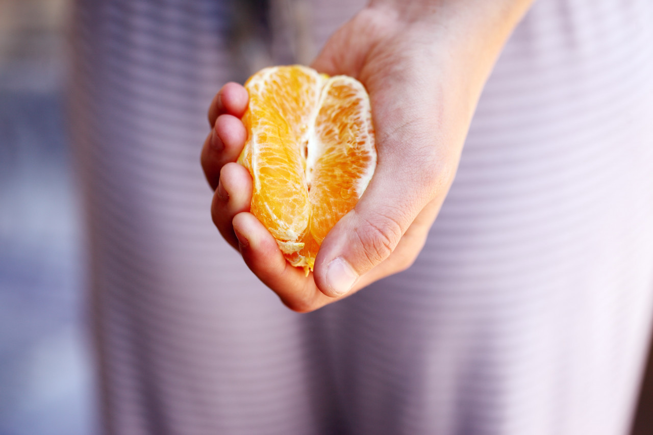 A person holding a peeled orange in her hand