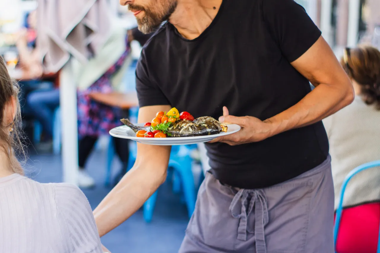 A waiter taking care of guests.