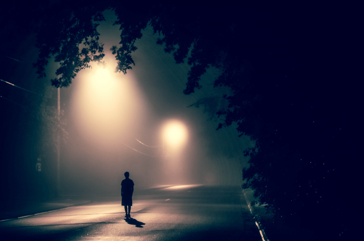 A person walking alone in the middle of the street at night.