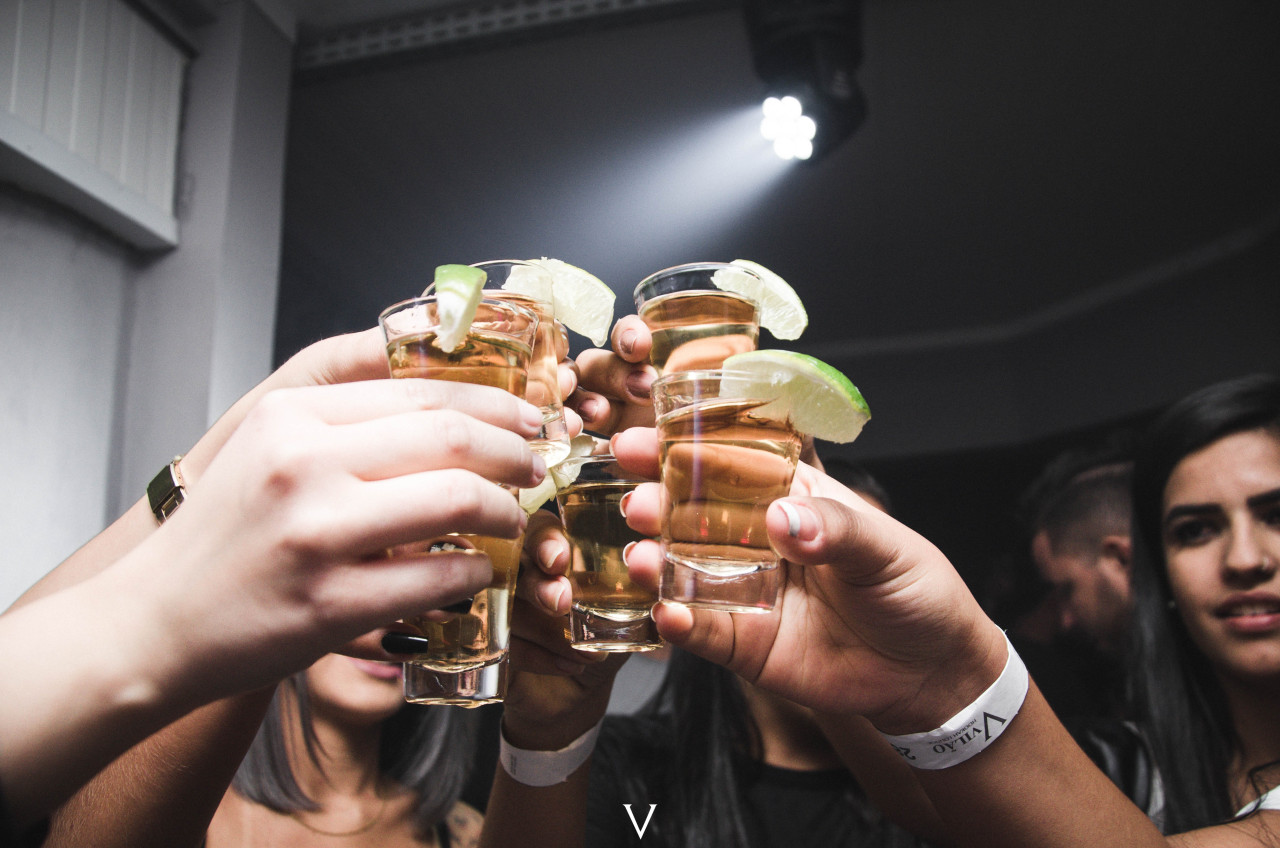 People holding cups of alcohol in the air.