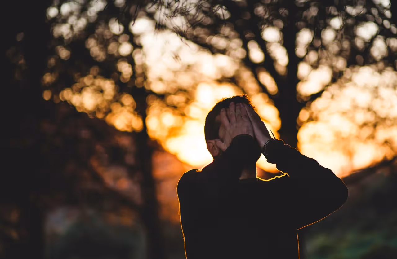 A stressed man holding his face.