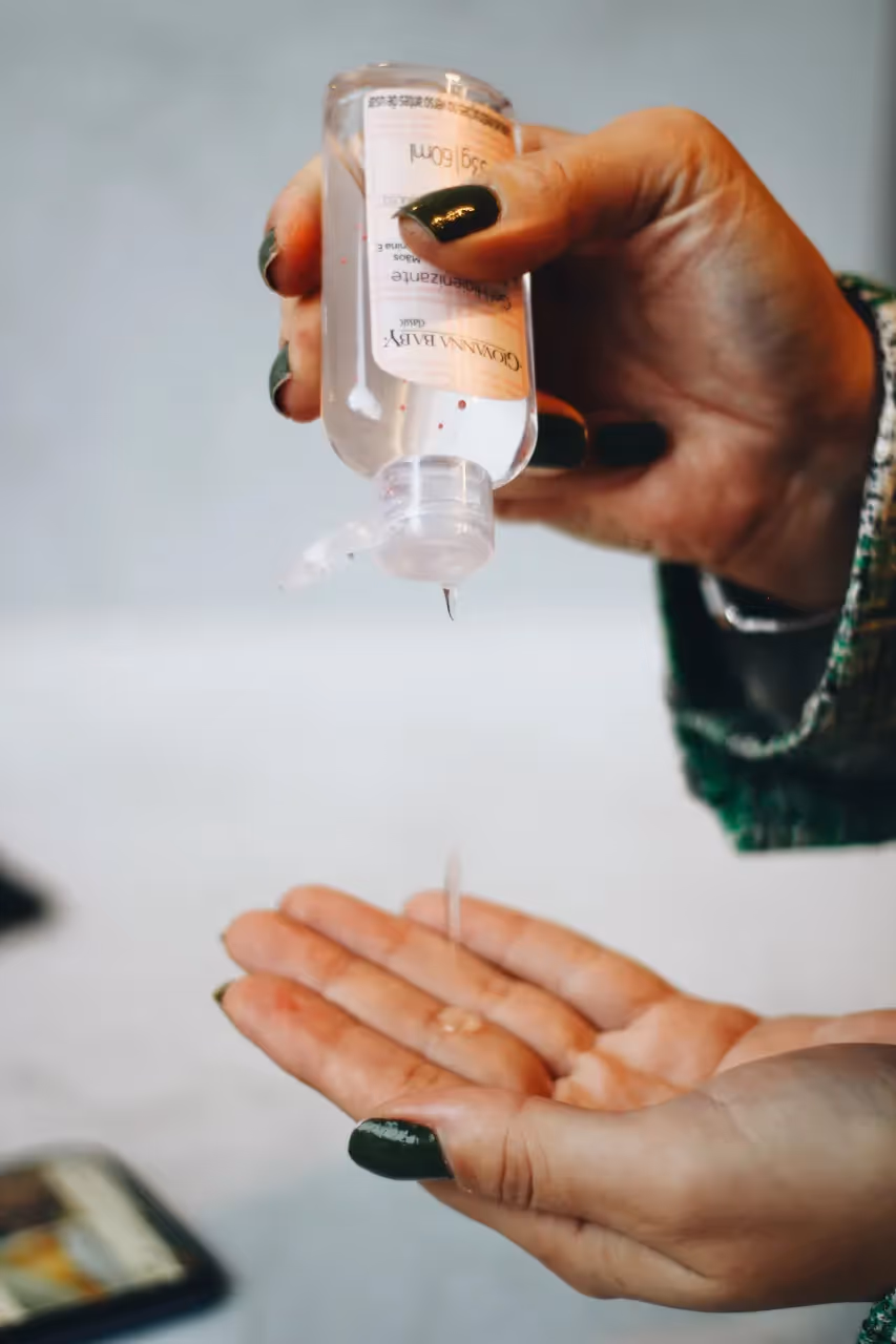 A woman putting hand sanitizer on her palm.