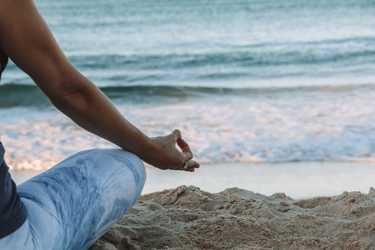 A man meditating on the beach.