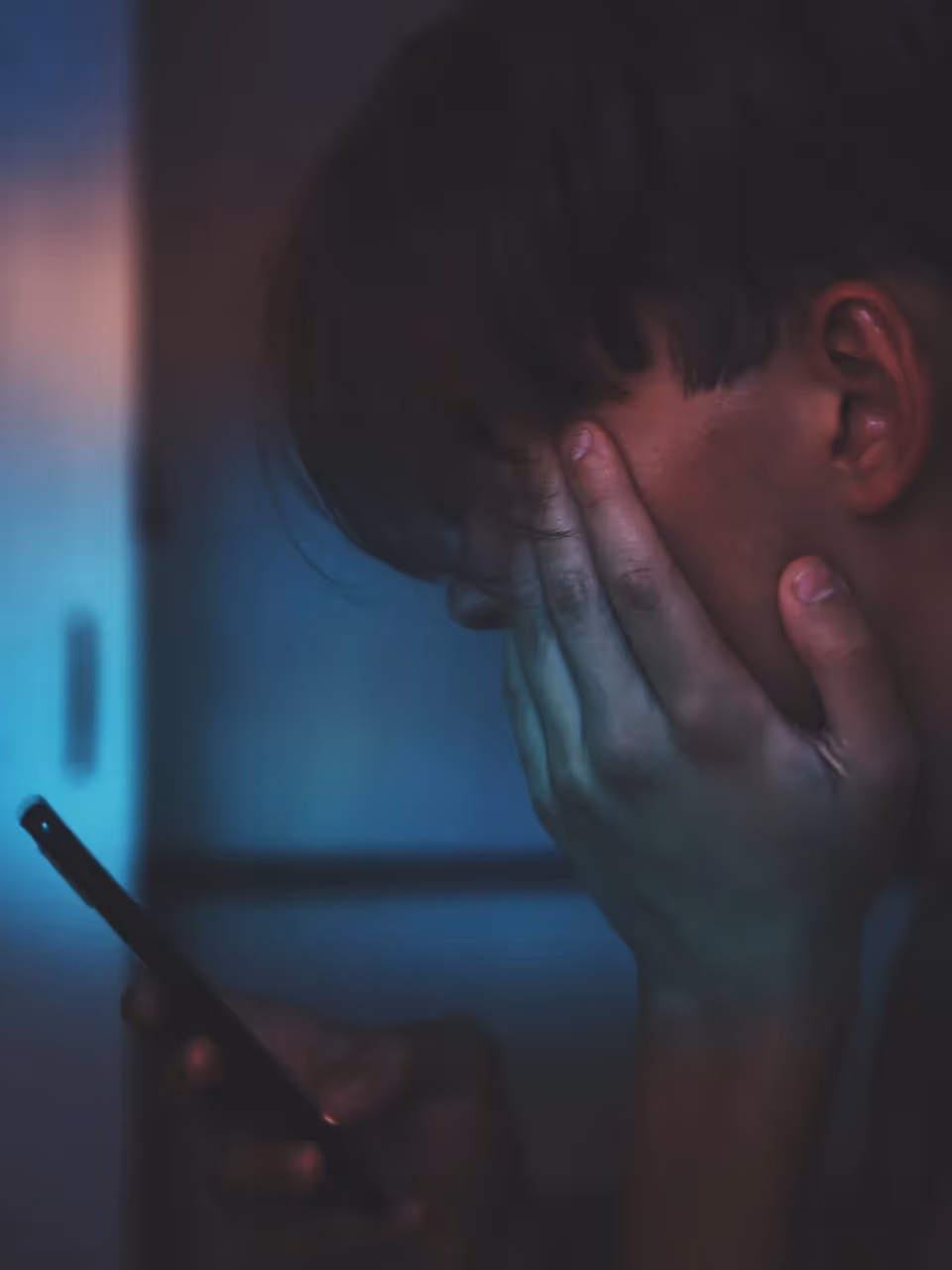 A depressed man looking at a phone.