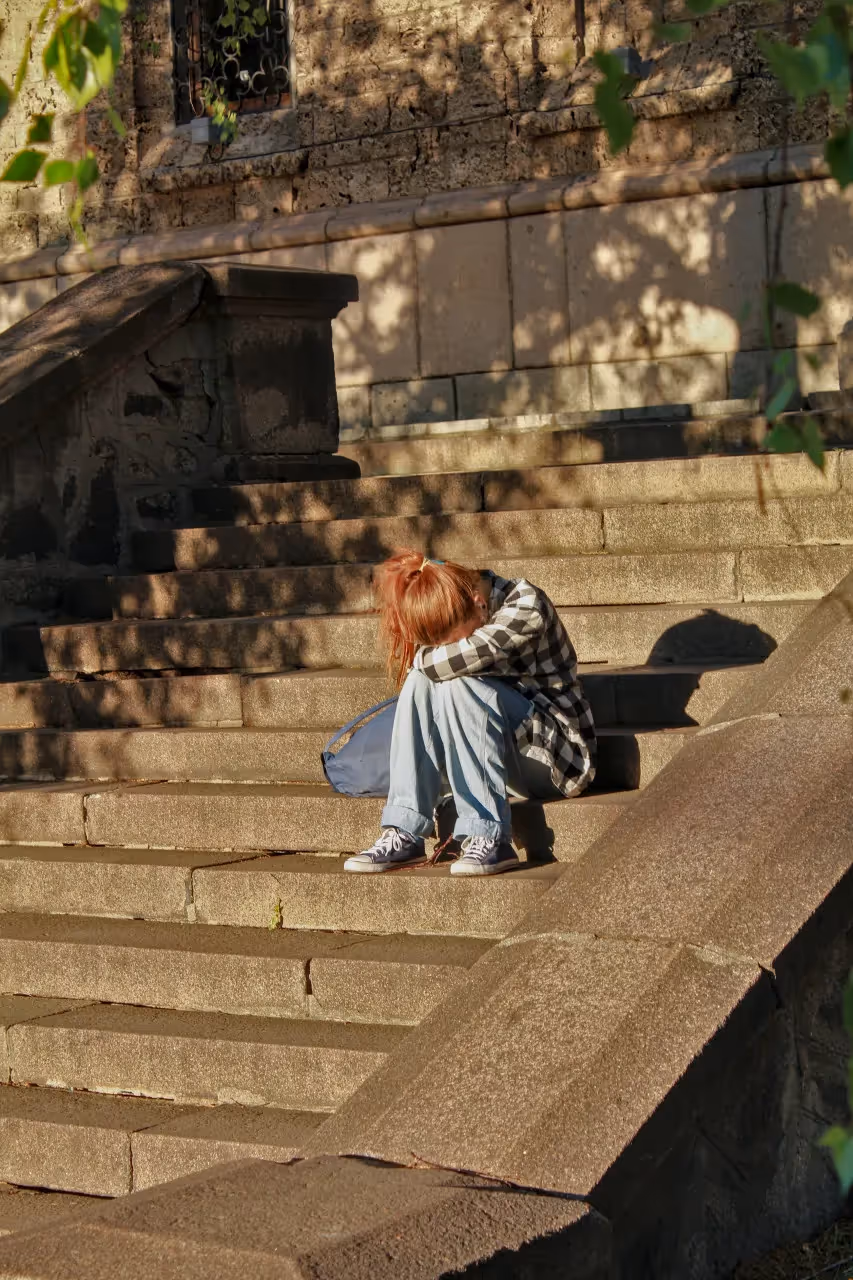 A sad girl sitting outside on concrete steps