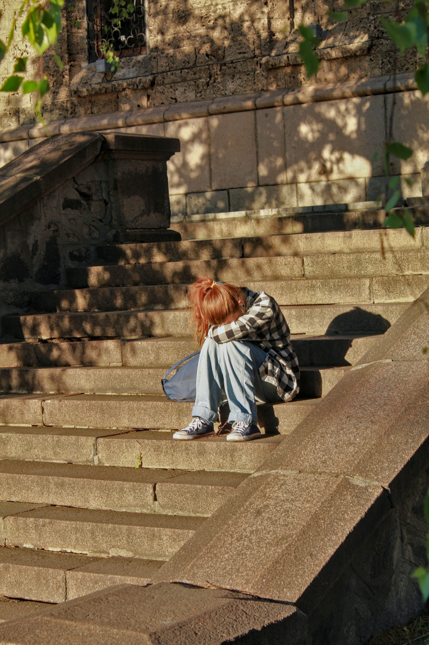 A sad girl sitting outside on concrete steps