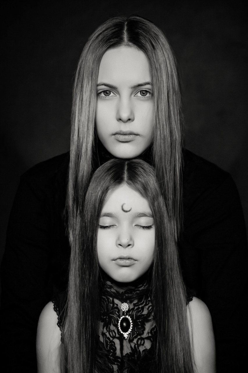 Daughter with her eyes closed and mom resting her chin on daughter's head
