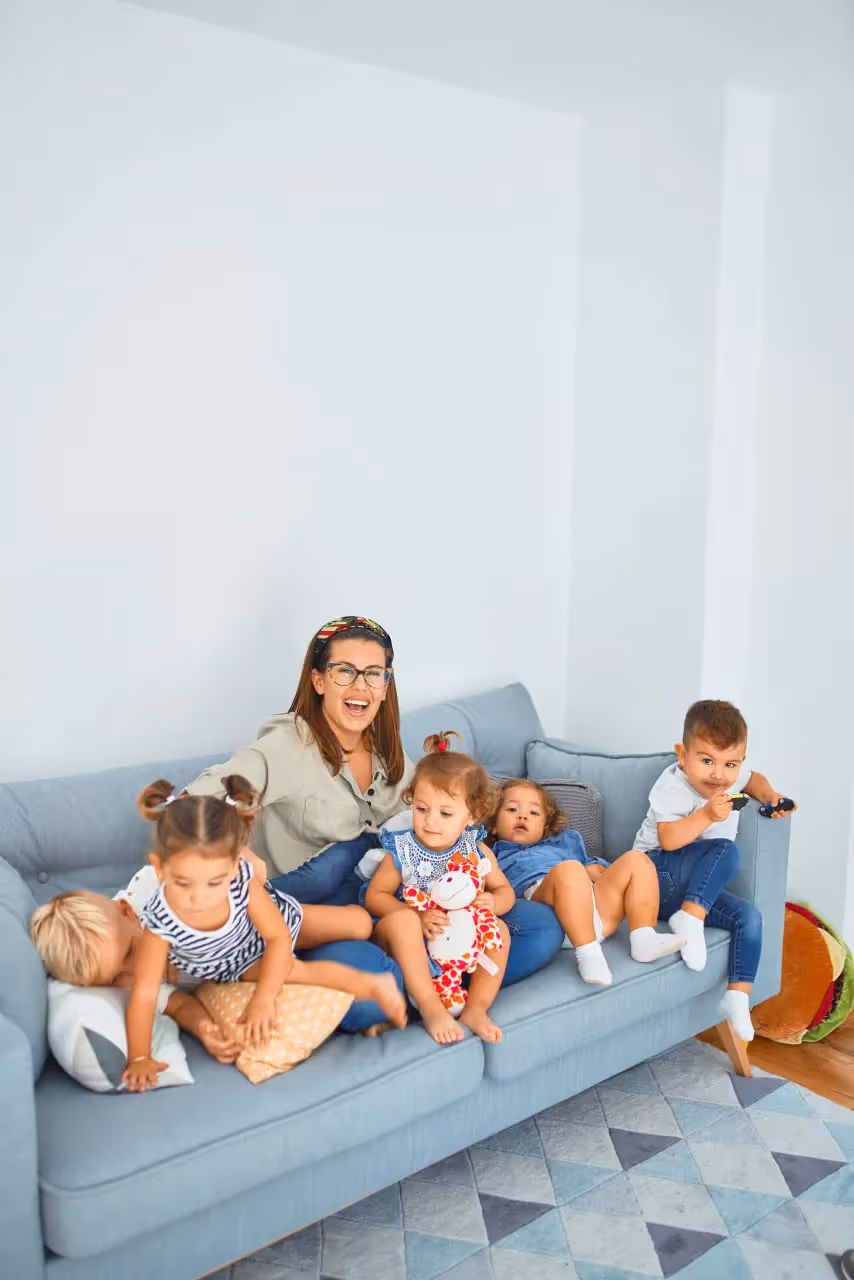 A mother sitting on the couch with 5 kids.