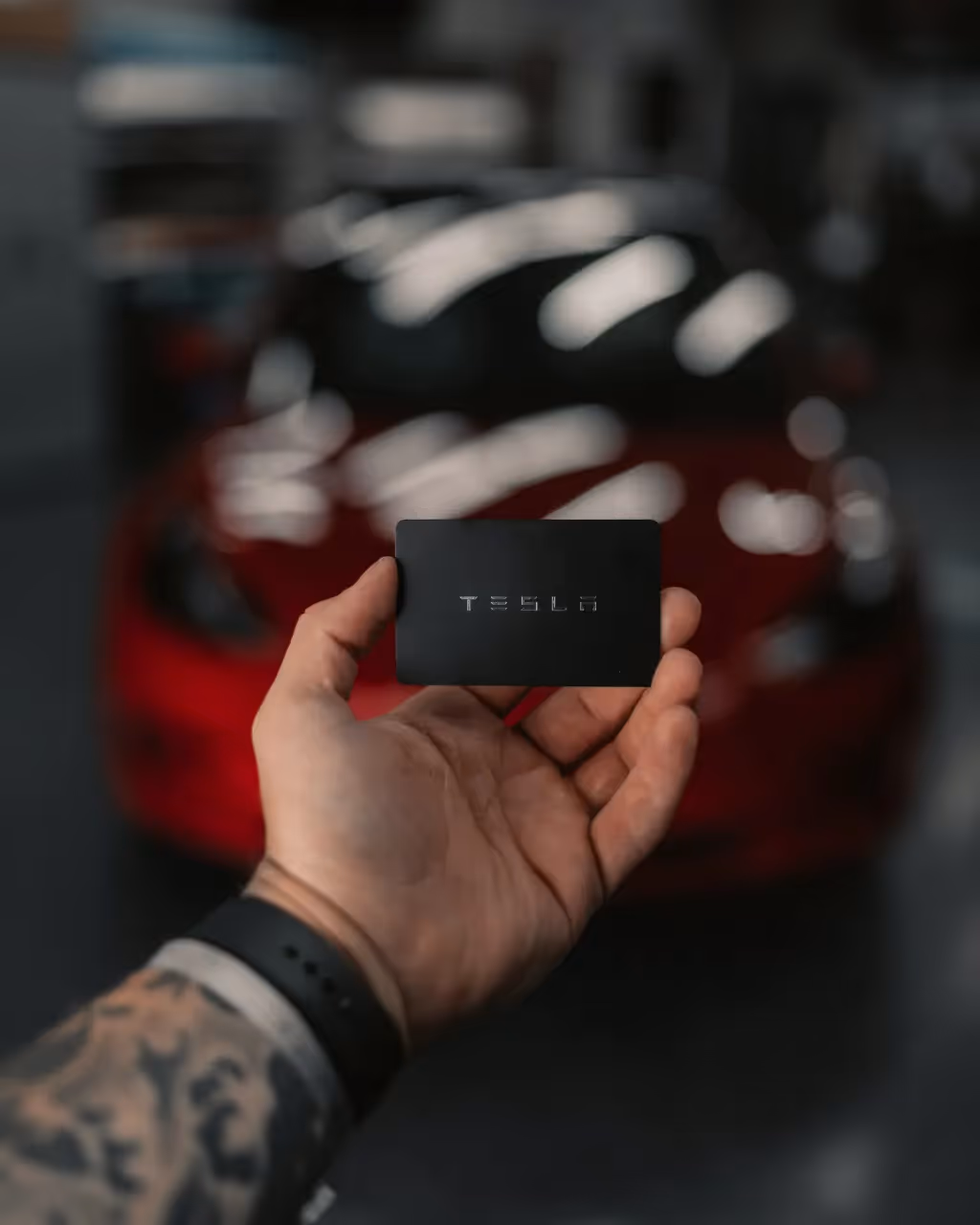 A person holding a card of Tesla, a tech company owned by Elon Musk.