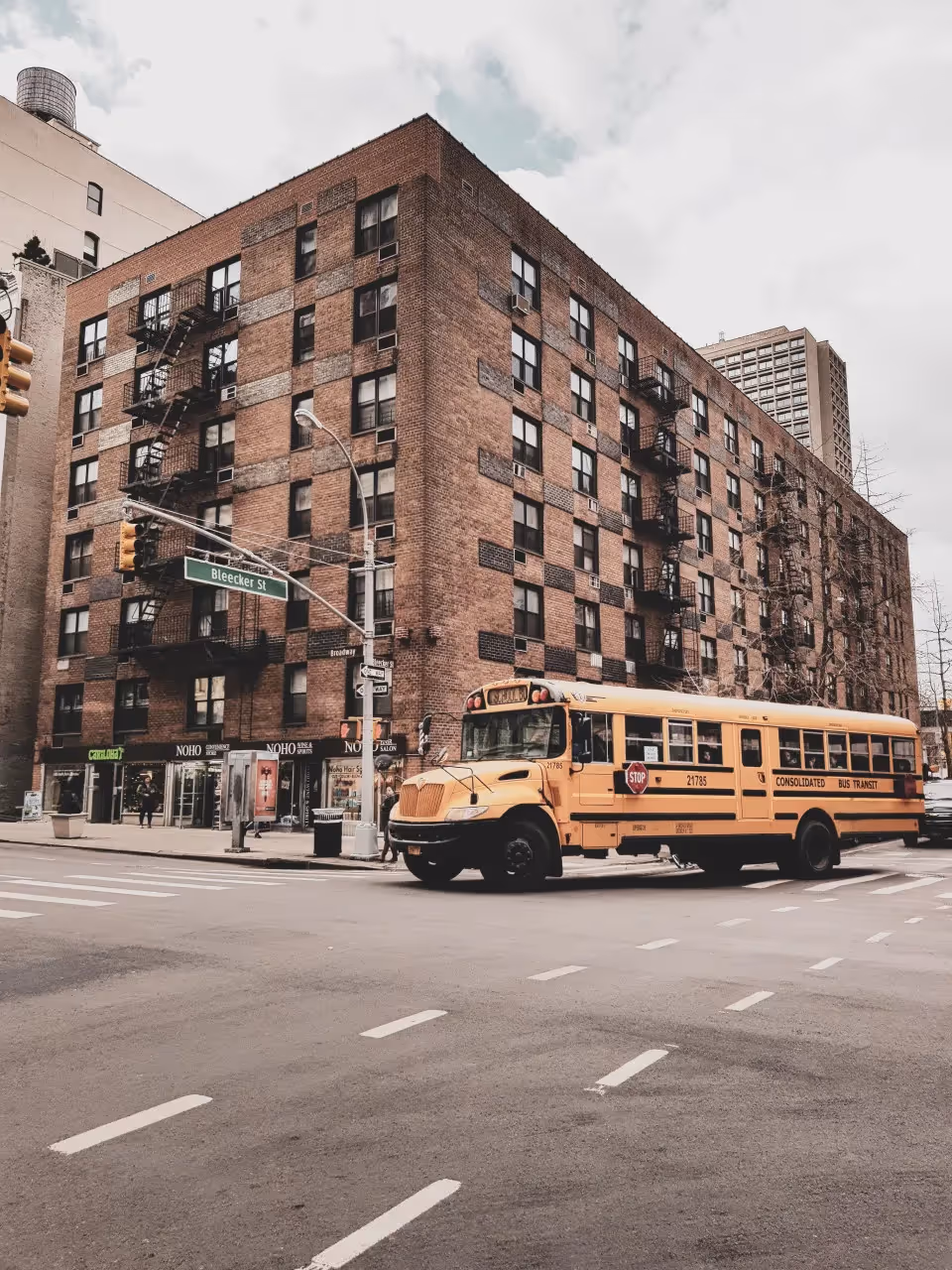 A school bus turning at an intersection outside a brick building