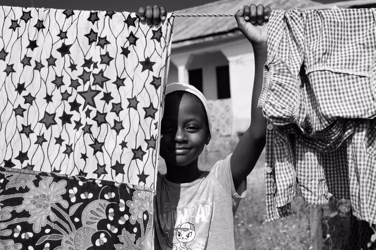 A child standing behind clothes hanging outside