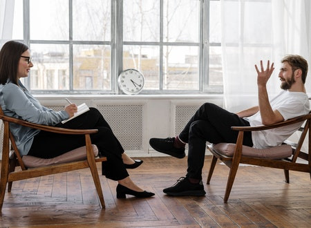 A man sitting across from a woman in a counseling session.