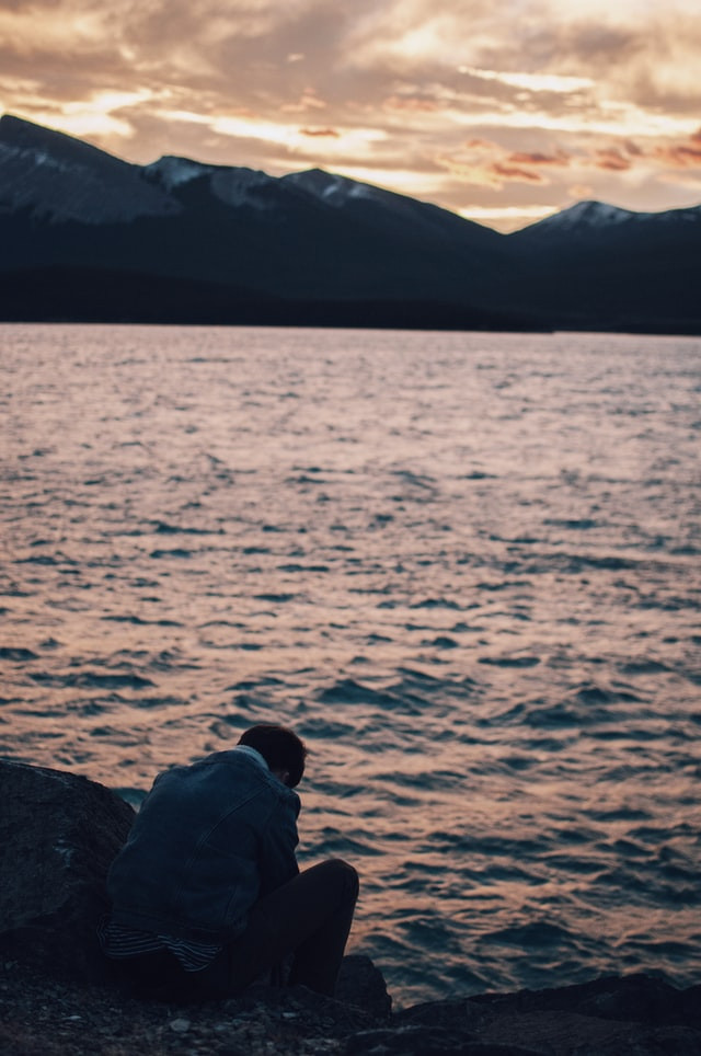 A person sitting on rocks overlooking the water
