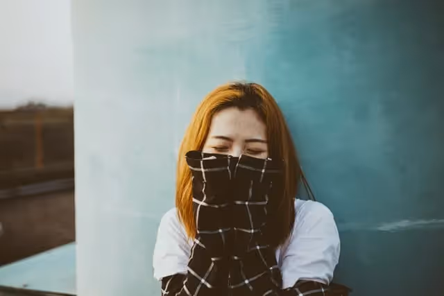 A woman standing against a wall with her hands over her mouth