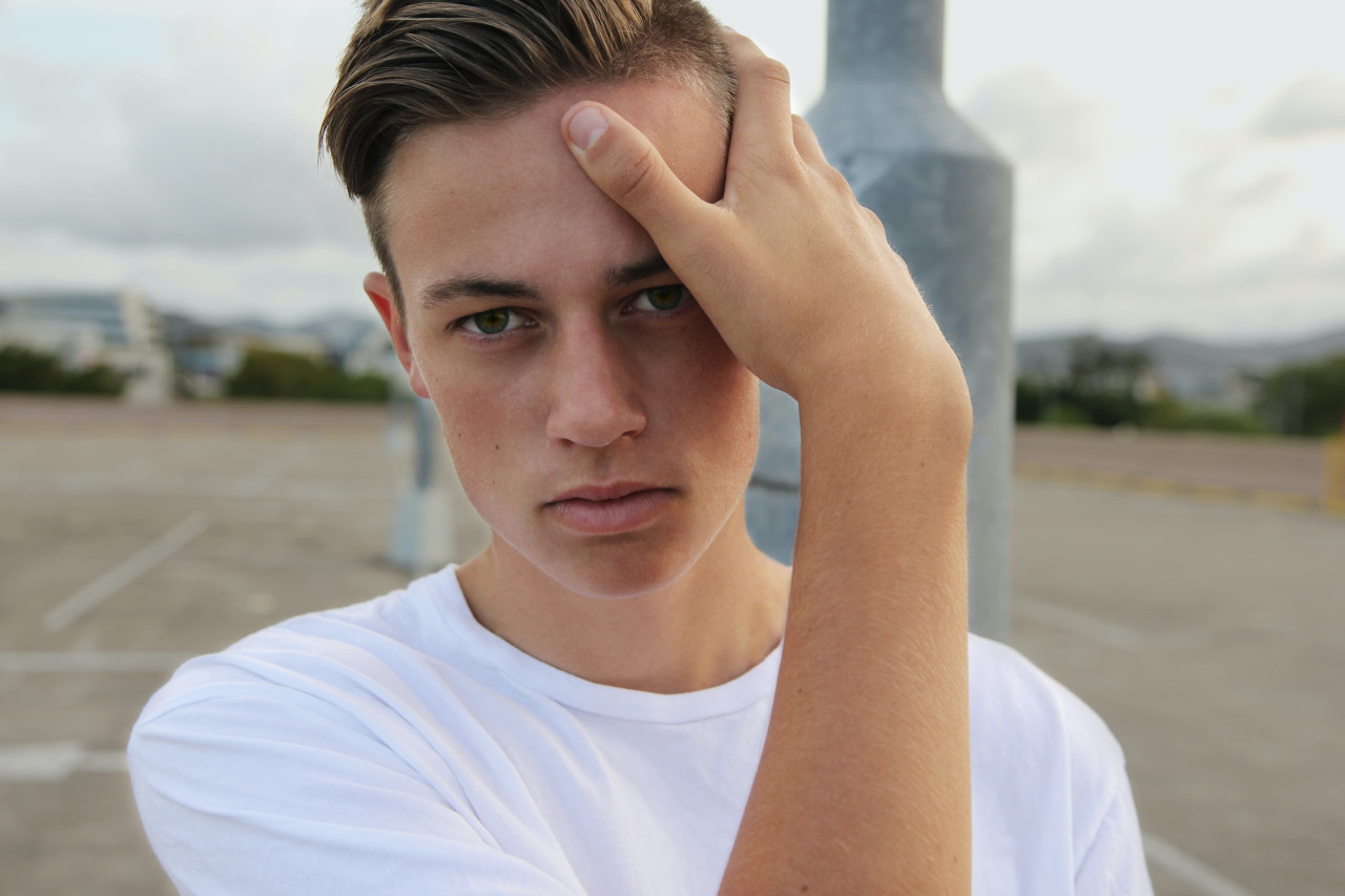 An adult child holding his head for a photo.
