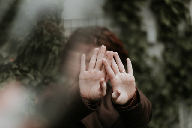 Person holding their hands out in front of their face