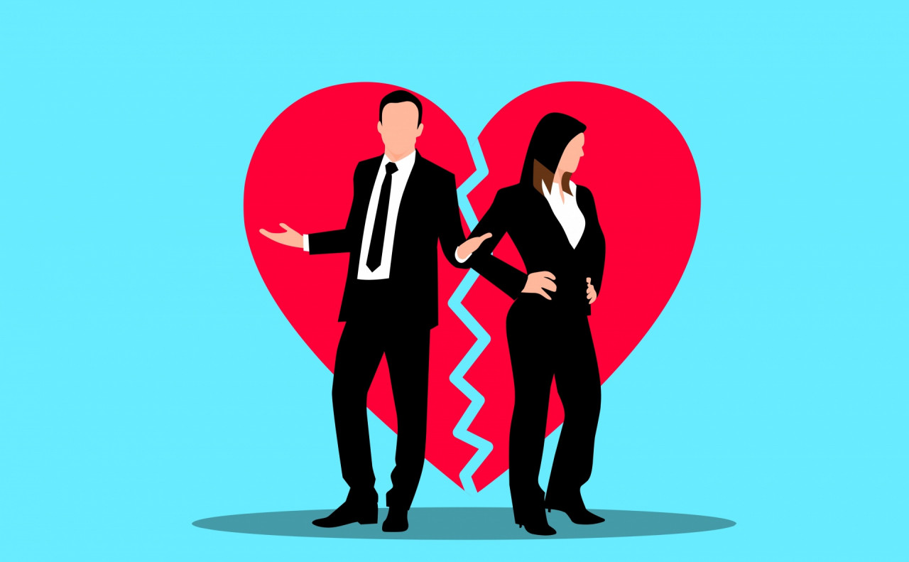 A man and a woman standing on opposite sides of a broken heart.