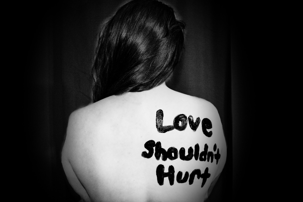 Woman with Love Shouldn't Hurt written on her back.