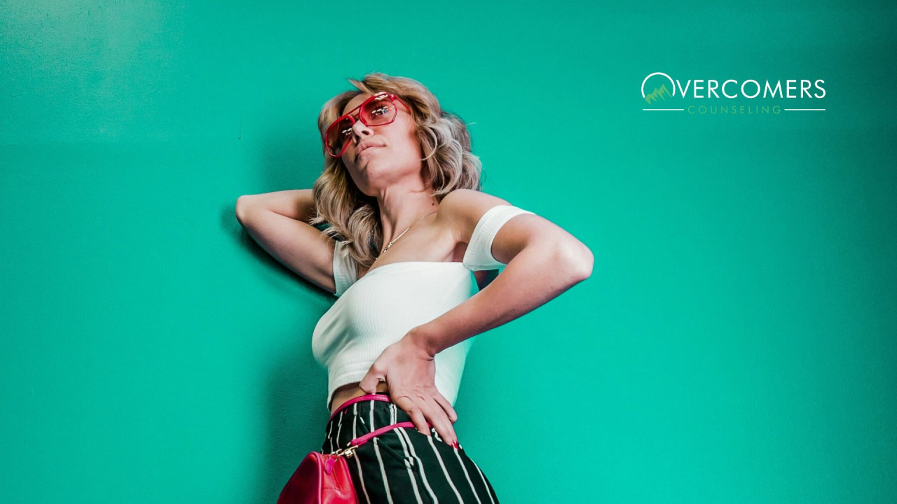 Woman in the glasses posing next to green wall